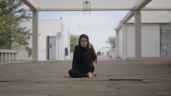 Centered Slomo of Girl Dressed in Black Sitting on Wooden Bridge alt