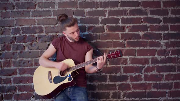 Man with Acoustic Guitar Leaning Against Brick Wall Composes Music Singing Songs Enjoy Life Medium