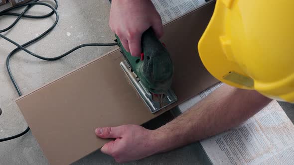 Skilled Man Sawing Wooden Laminate Board with Electric Jig Saw