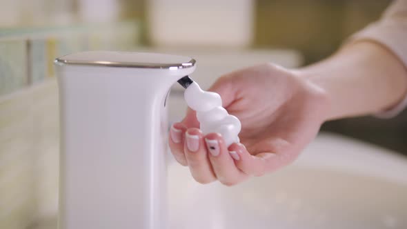 The Girl Washes Her Hands Using an Automatic Soap Dispenser in the Bathroom alt