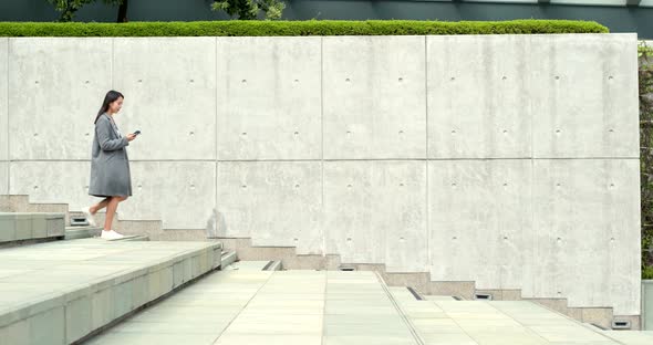 Business woman working on cellphone with walking downstairs at outdoor alt