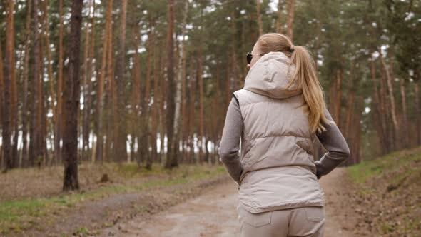 Beautiful Woman in Jacket Waistcoat Walk Alone Trailpath in Pine Forest in 