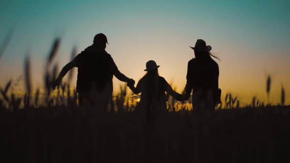 Happy Family Silhouette Farmers Working in a Wheat Field at Sunset alt