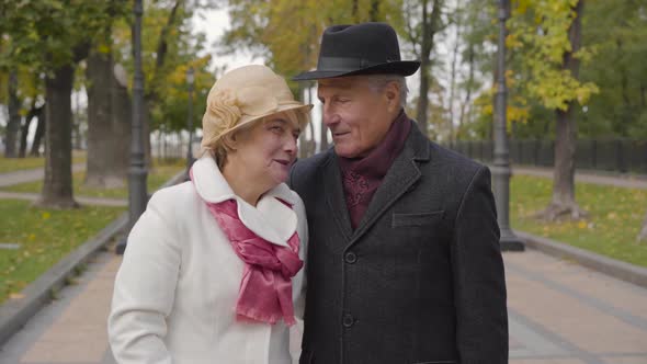 Mature Cucasian Couple in Elegant Clothes Standing in the Autumn Park and Talking alt