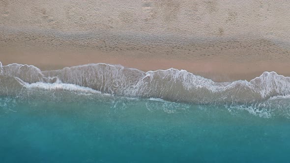 Top Down View of Sandy Beach and Turquoise Sea Waves at Shore Edge alt