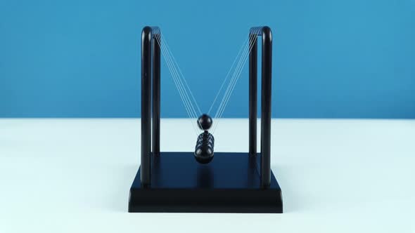 Table Pendulum Balance Newton Balls Small On A Blue Background.