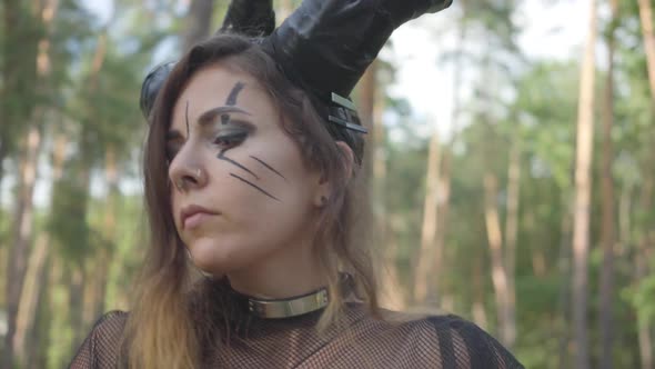 Elegant Young Woman in Theatrical Costumes of Devil or Maleficent Dancing in Forest Showing alt