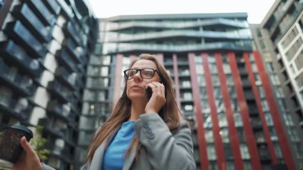 Formally Dressed Woman Walking Down the Street in a Business District with Coffee in Hand and alt