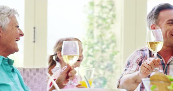 Family toasting a glasses of wine and juice on dining table alt