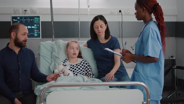 African American Pediatric Nurse Explaining Recovery Treatment to Worried Parents alt