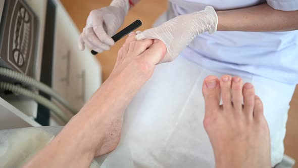 Pedicurist Doing Professional Medical Pedicure Procedure in Beauty Salon Using Nail File. Foot