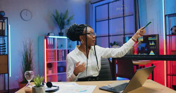 African American Woman which Explaining Export and Import Indicators Drawn on Glass Board on Camera alt