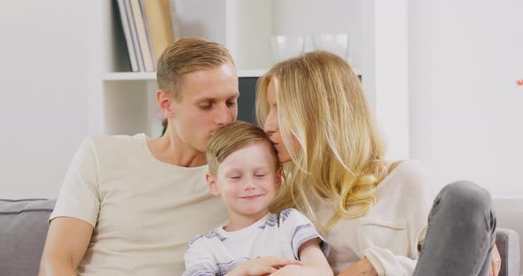 Happy Young Father and Mother Couple Kissing on Head Their Kid at Home Family Time Relax with Young alt
