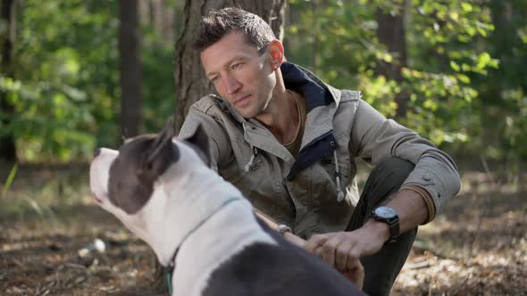 Smiling Caucasian Man Looking at Dog Walking Away in Slow Motion in Forest alt