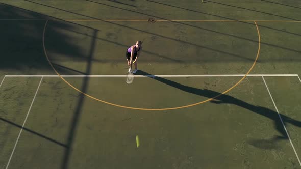 Aerial footage of a female tennis player playing tennis on a tennis court alt