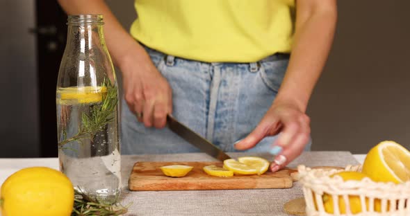 Female Hand Cut Lemon Making Detox Healthy Water with Lemon and Rosemary alt