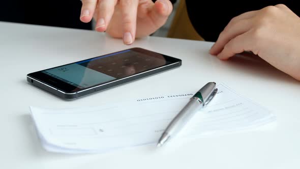 Closeup  Footage of Young Businesswoman Calculating Money Before Filling Empty Bank Cheque alt