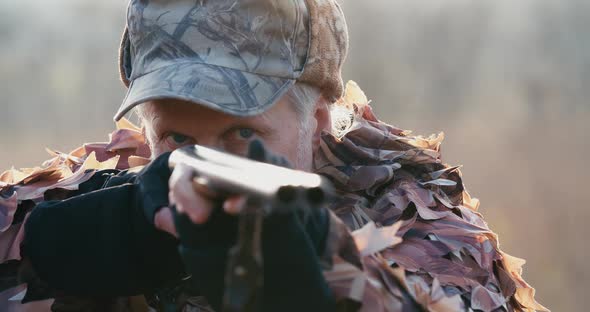 Portrait of Hunter in Hunting Equipment Aims With the Rifle, Lies in Wait in the Field Sunset Light alt