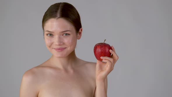 Young beautiful girl holding apple smiling and enjoying natural skin care alt