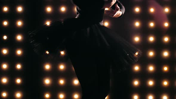 Silhouette of ballerina in black tutu is dancing ballet in the dark studio.