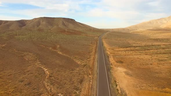Aerial view of an empty road in dryland of Fuerteventura. alt