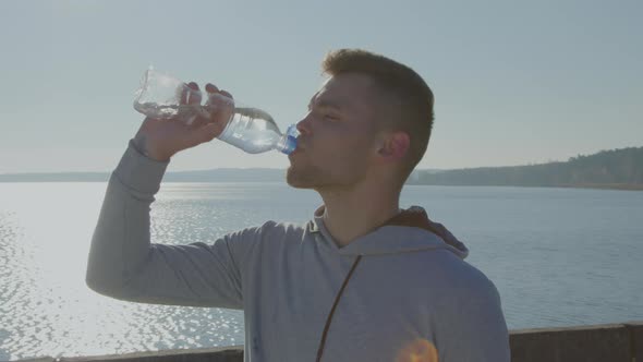 Young Athletic Man Is Drinking Water