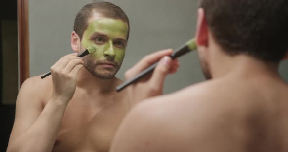 Attractive male using beauty cream product for skin health in Front of The Mirror