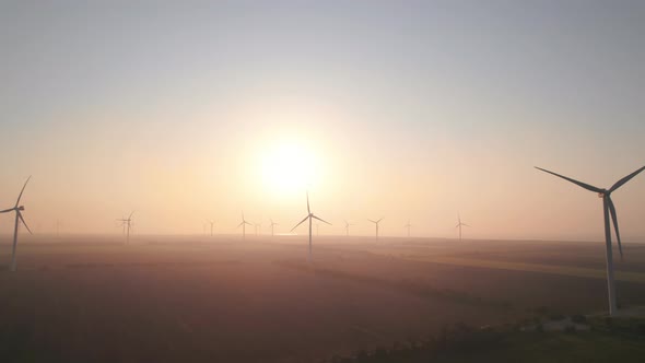 Windmills with rotating wings at sunrise or sunset or sunrise.