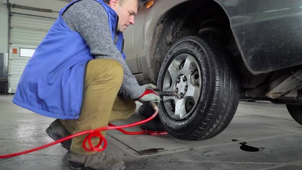Worker install the wheel on a car