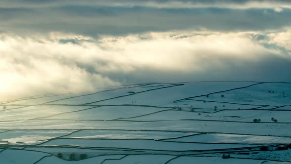 Time-lapse footage of the snow covered fields with their dry stone walls enveloped in low clouds, ne alt