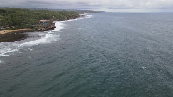 Aerial view of tropical beach in Gunung kidul, Indonesia with green and rocky cliff. alt
