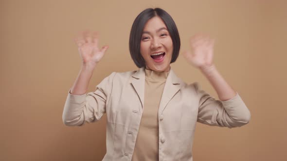 Happy asian business woman waving her hand for greeting and looking at camera isolated