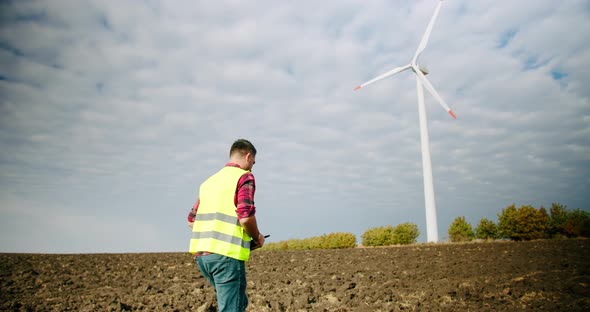 The Engineer Goes to the Windmills Power Turbines with the Tablet in His Hand alt