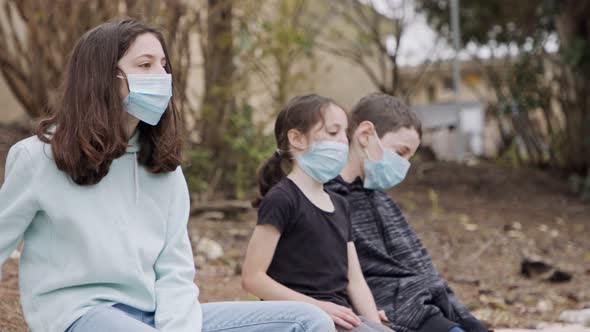Coronavirus pandemic - kids wearing face masks to avoid contagion sitting bored alt