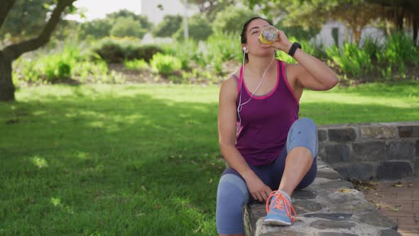 Caucasian woman drinking water in a park alt