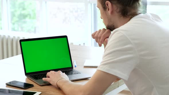 Handsome Specialist Working on Laptop Computer with Green Screen Mock Up Display at Home alt