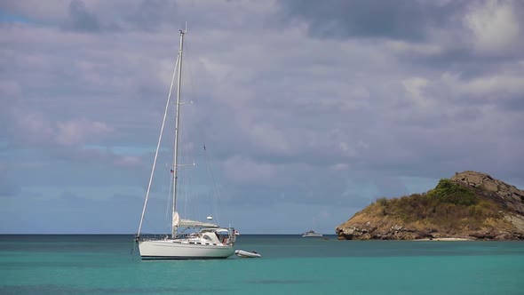 Lonely White Luxurious Sailboat Yacht in Caribbean Ocean Harbor Near the Rock
