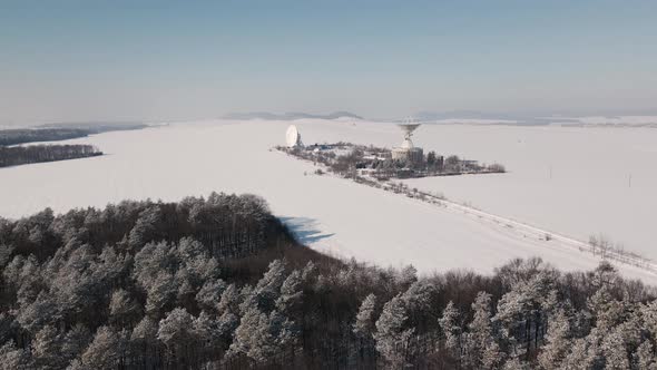 Cinematic Aerial View of the Space Communication Station in Snow Covered Field at Sunny Winter Day