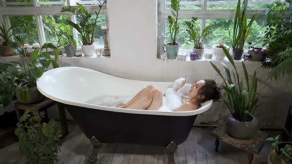 Woman lying in the bathtub and having fun. 