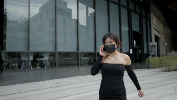 A Sad Woman Wearing Black Medical Mask and Talking with Mobile Phone alt