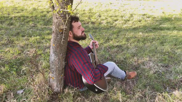 Real time shot of man playing acoustic guitar outdoors