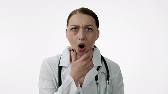 Caucasian Woman Doctor Is Very Surprised, Opens Her Mouth, Holds Chin with Hand alt