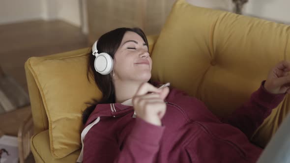 Close Up of Young Happy Woman Lying on Sofa and Listening to Music alt