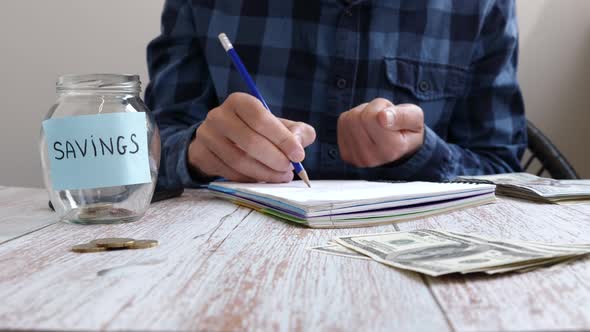 Man putting money coins into glass jar with inscription savings. Saving money concept alt