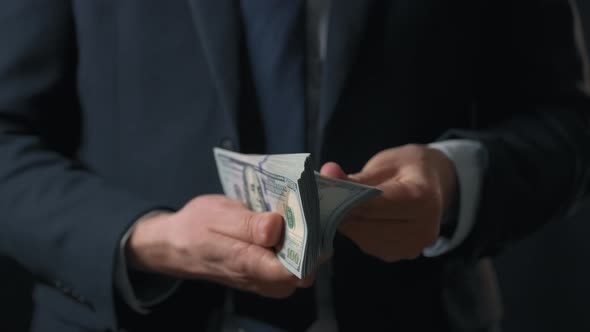 Formally Dressed Man Counting US Dollar Bills alt