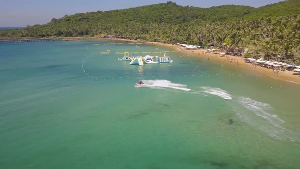 Aerial Tracking Fly Over a Tourist in a Resort Riding a Fast Jetski on Summer alt
