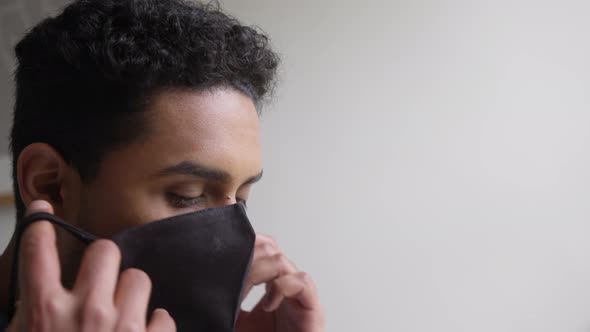 Close Up Of Man Putting On Face Mask In Bedroom Before Leaving Home During Health Pandemic