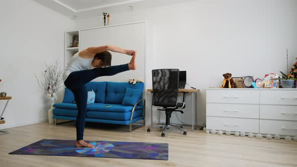 Young Woman Balancing On One Leg During Yoga Exercise At Home