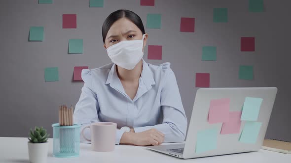 Asian woman angry wearing mask and working on a laptop