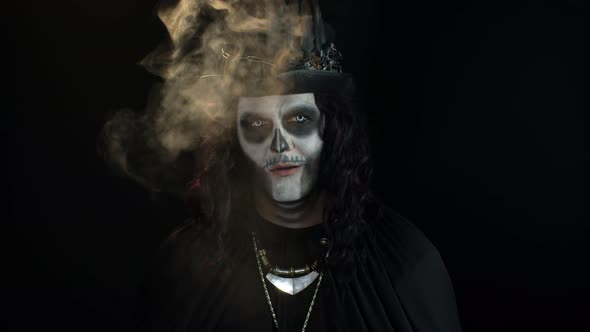 Sinister Man with Halloween Skeleton Makeup Exhaling Cigarette Smoking From His Mouth and Smiling alt